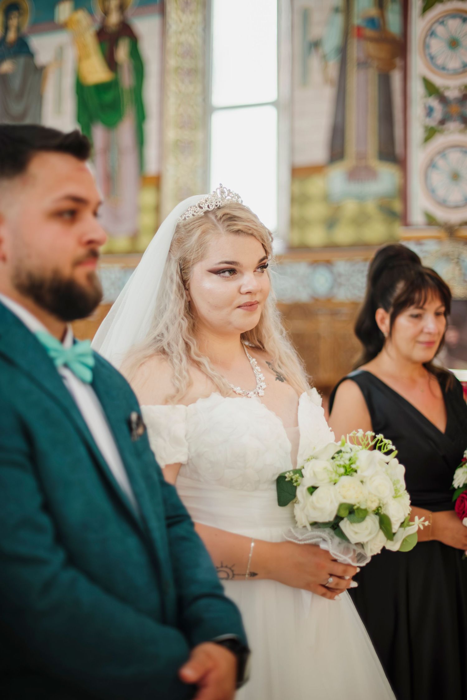 Wedding ceremony in ornate church with bride holding white floral bouquet.