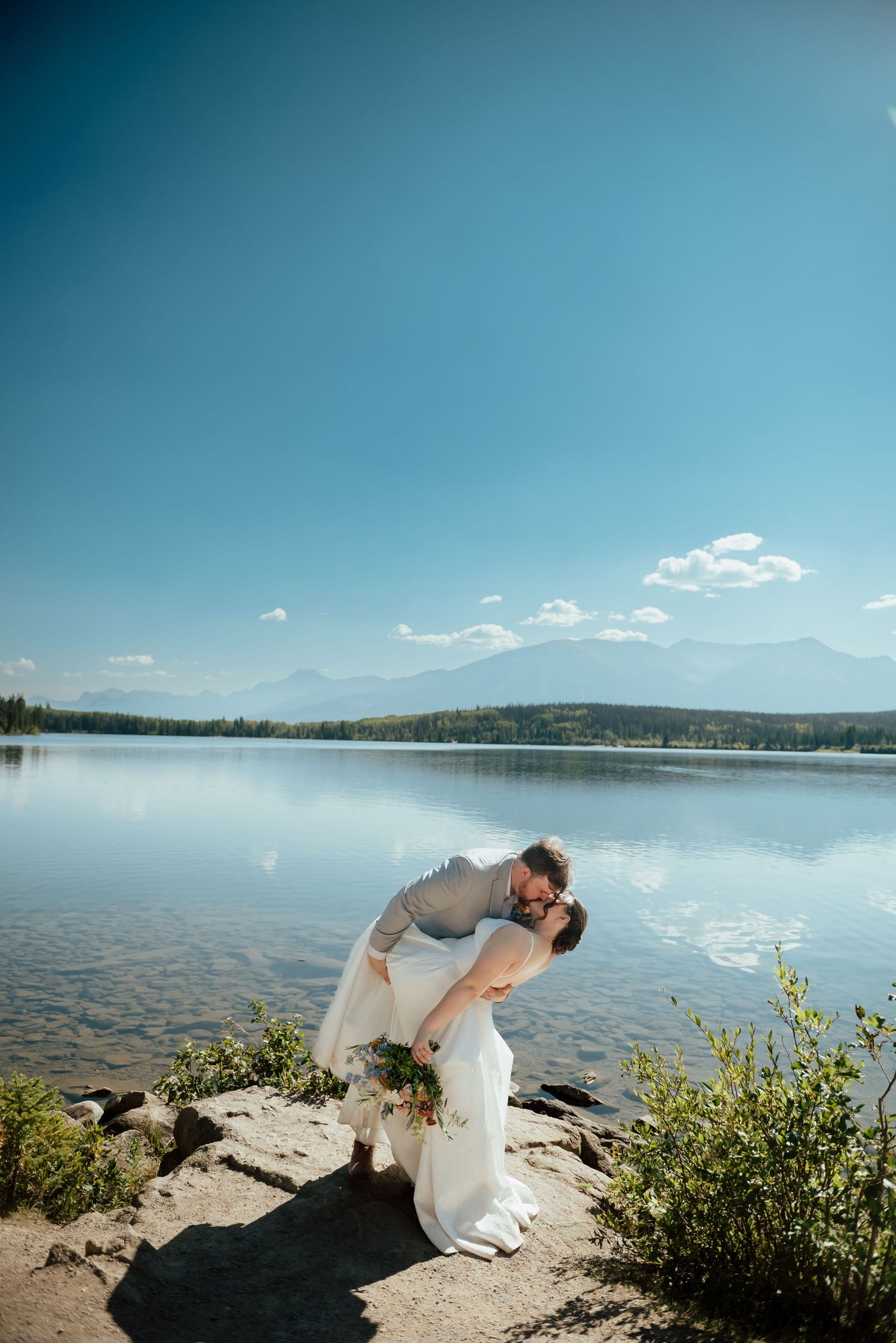 A couple shares a romantic moment outdoors in winter, with the person in dark attire lifting their partner wearing white clothing.