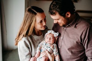New parents gazing at their newborn baby girl in a floral outfit.