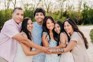 Joyful extended Asian family hugging together outdoors in a park setting.