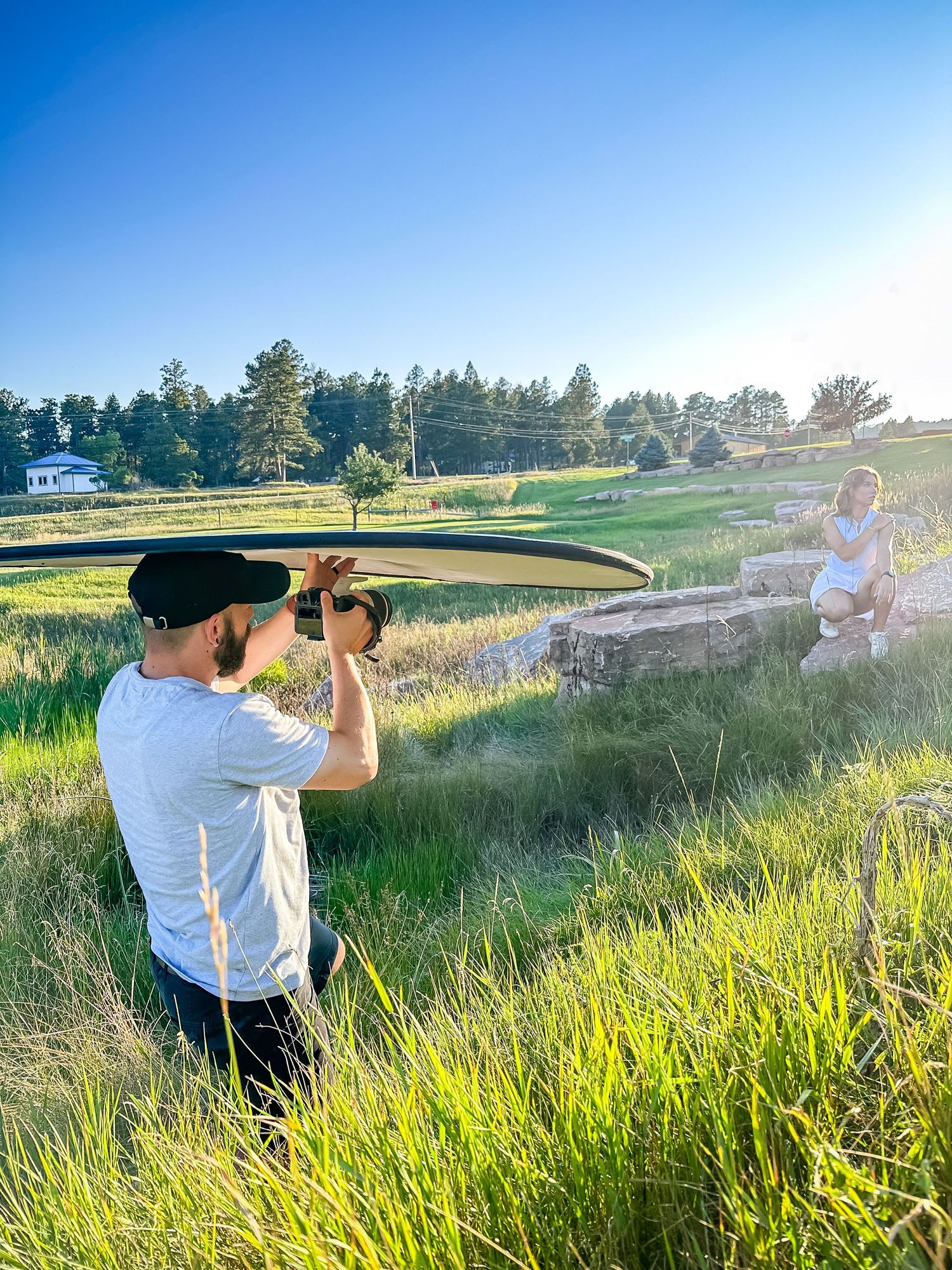 Photographer taking pictures in a grassy field during golden hour.