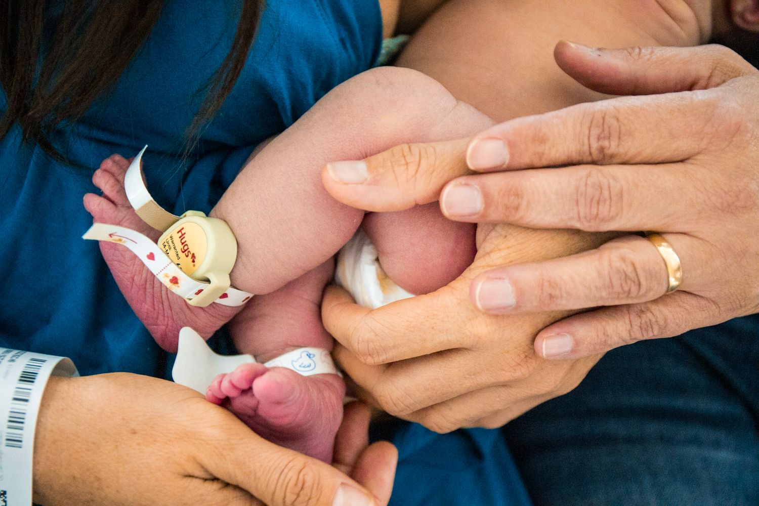 Close-up of tiny newborn feet being held by caring hands.