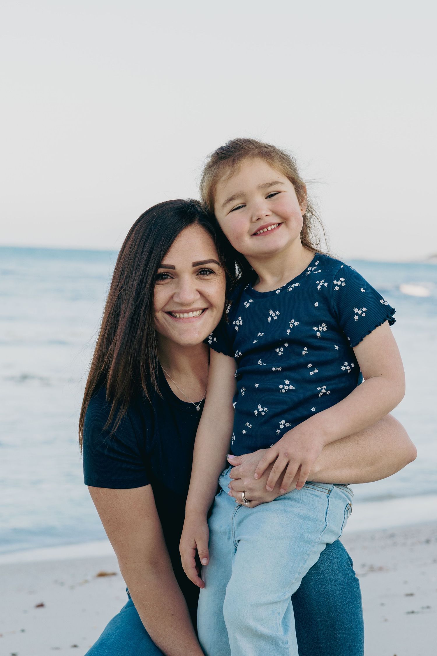 Mother and daughter share joyful moments together on a beach during a sunny day.