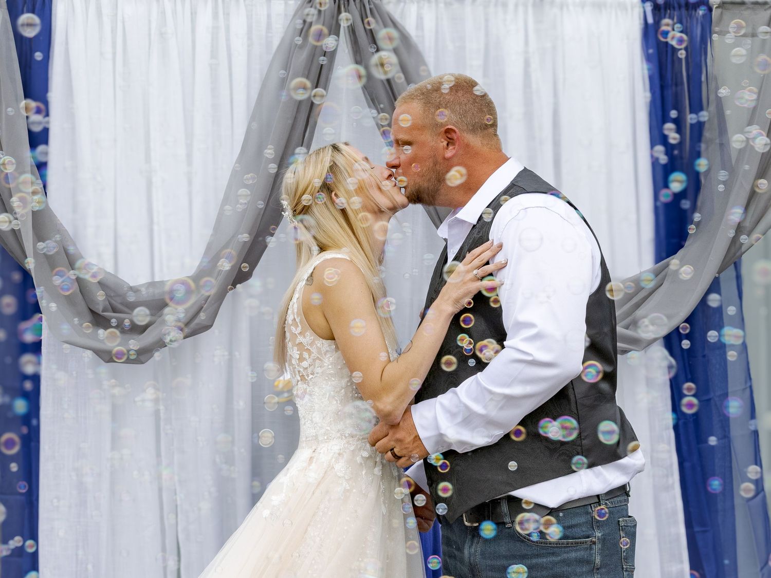 A bride and groom share their first kiss surrounded by bubbles at an elegant wedding ceremony.
