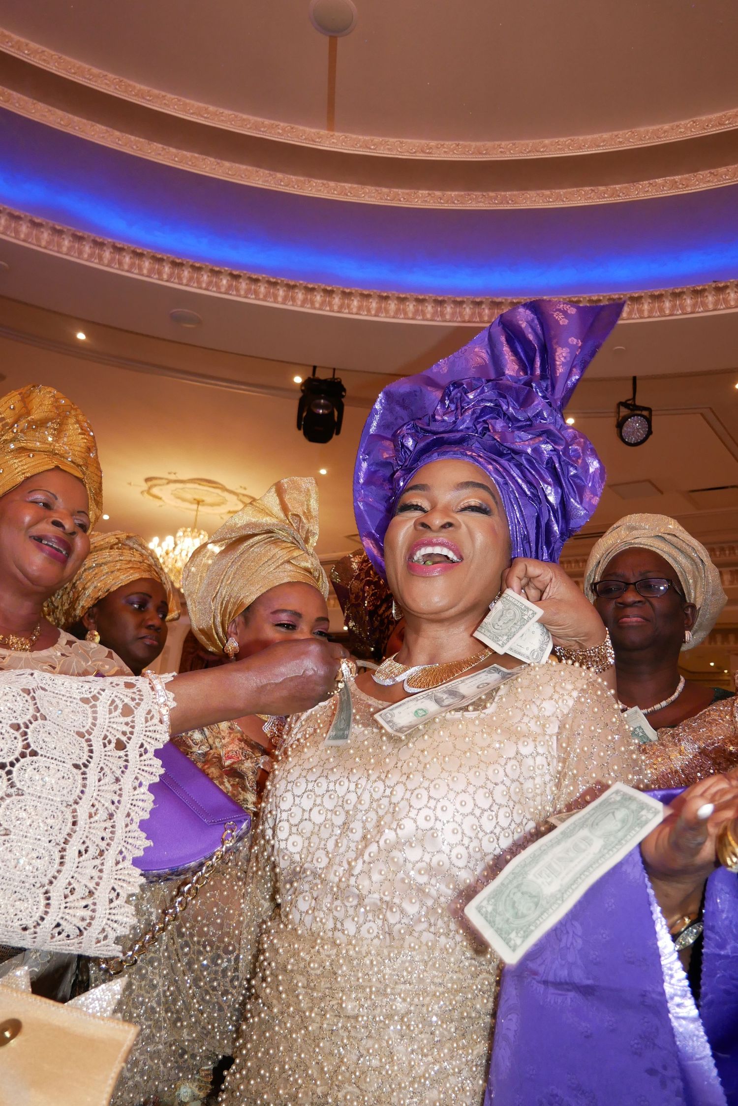 A joyous celebration with traditional African headwraps and formal attire under decorative lighting.