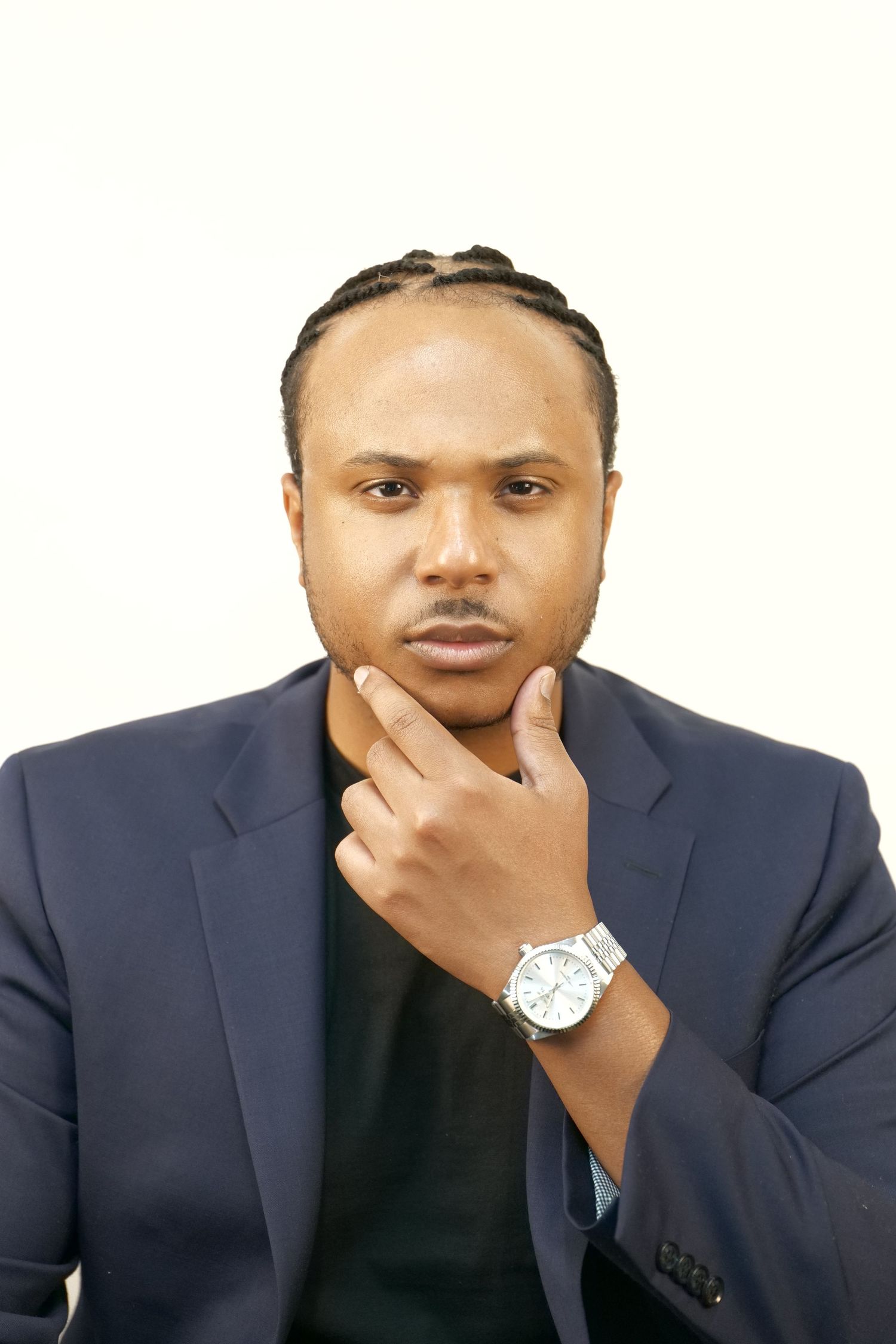Professional portrait against white background featuring formal attire and thoughtful pose.