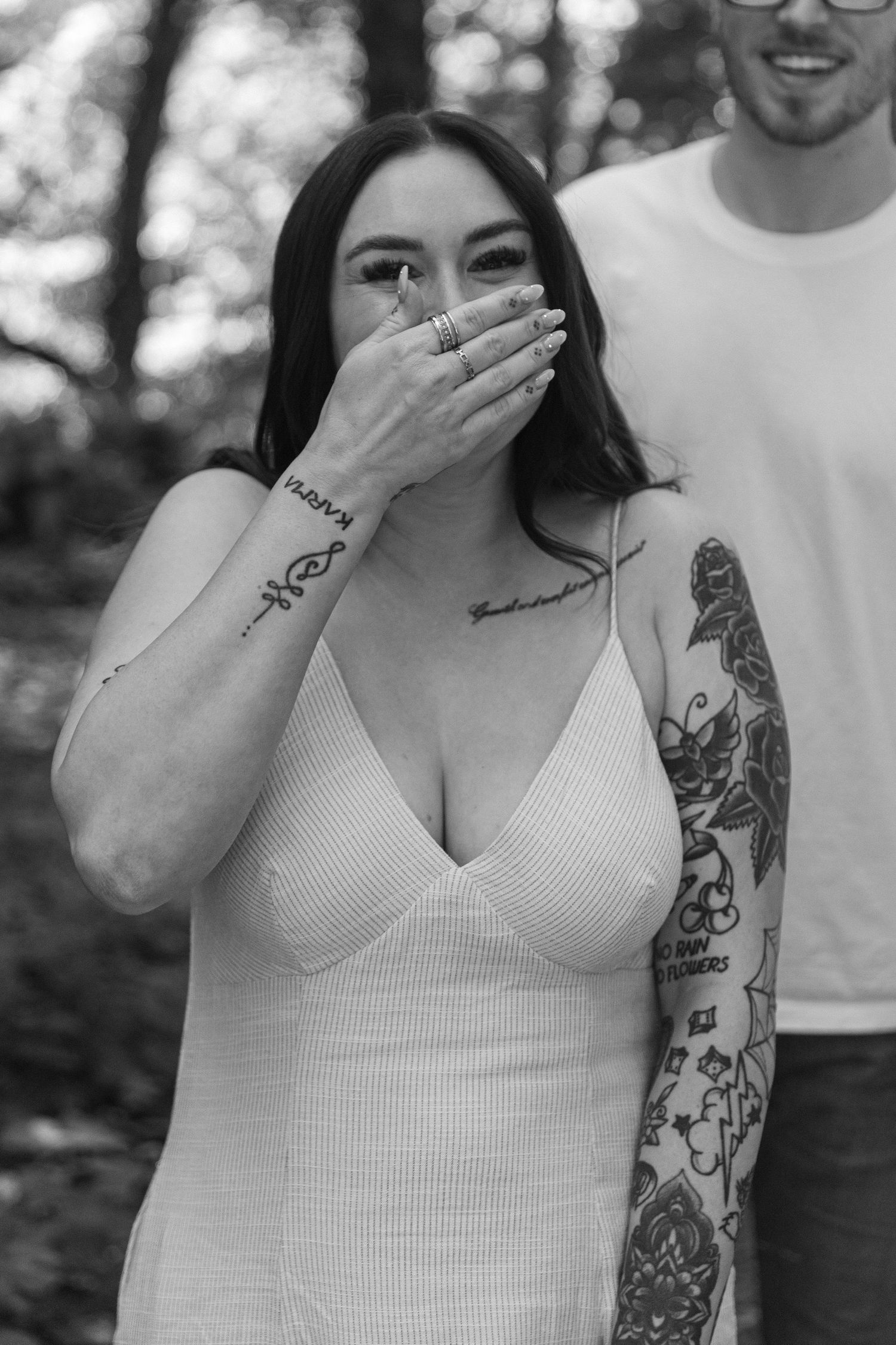 Black and white portrait showing joyful expression with visible tattoos.