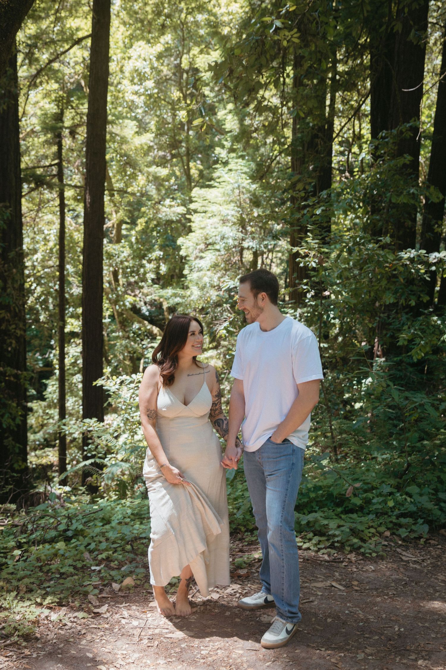 Couple in casual attire sharing a moment while walking along forest trail.