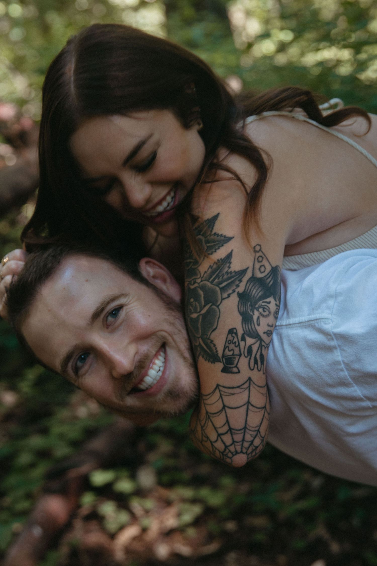 A joyful close-up moment shared between a couple in a forest setting.
