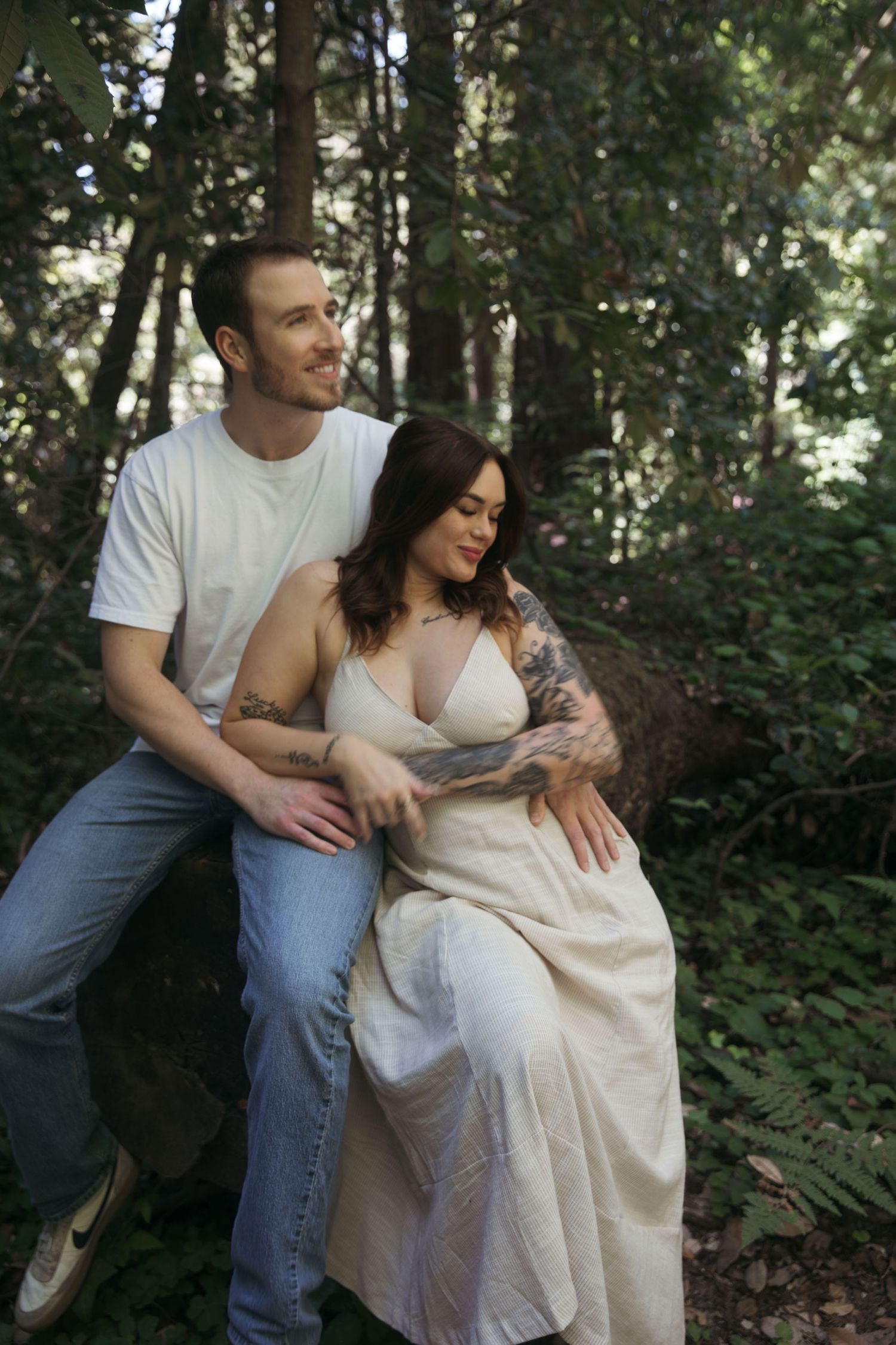 A tender embrace captured between a couple in a dreamy forest setting.