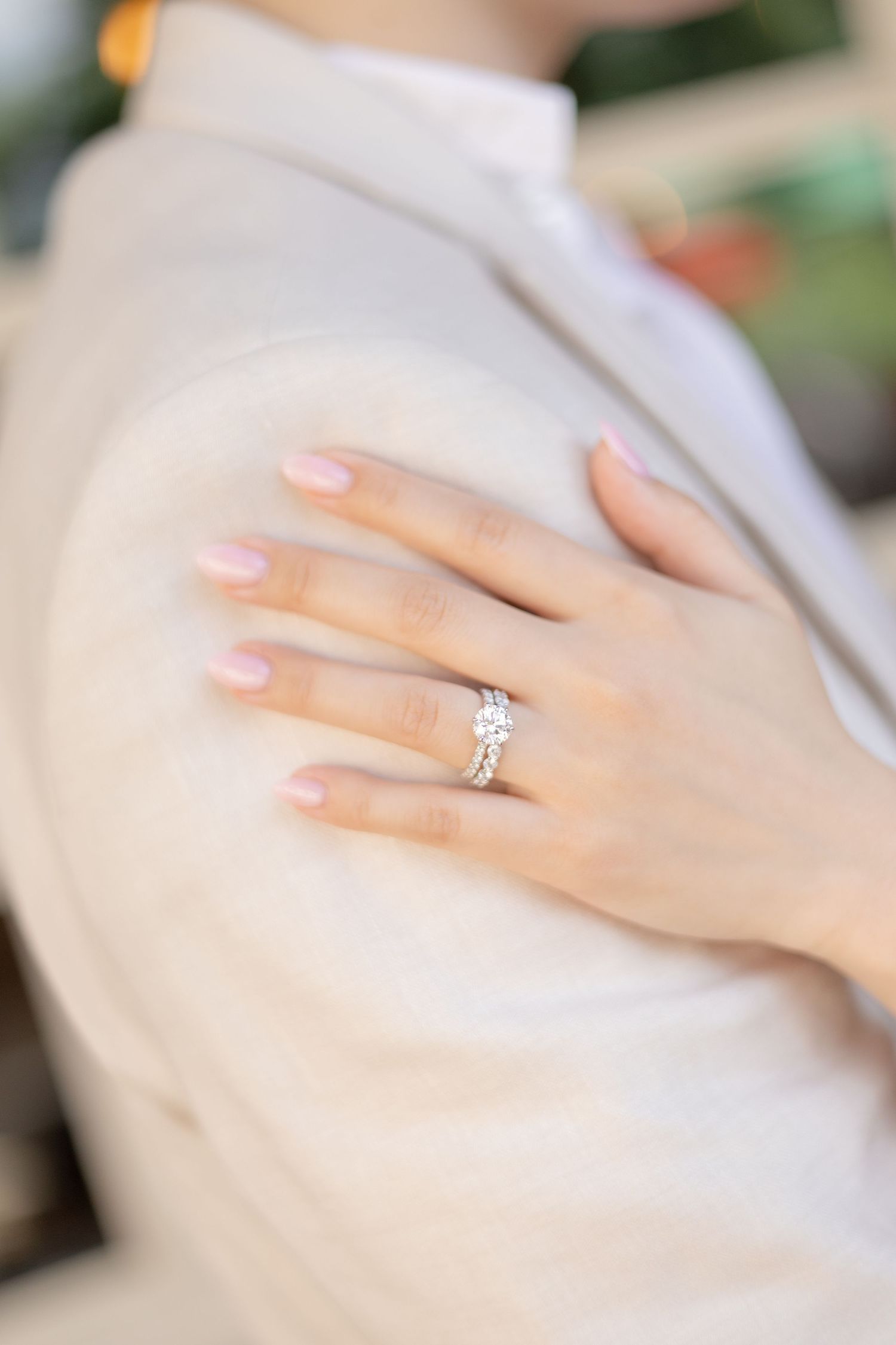 Close-up of an elegant diamond engagement ring and french manicure on a woman's hand.