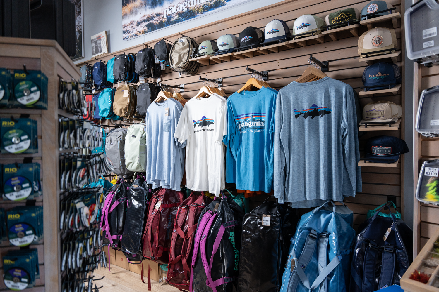 Retail display of fishing apparel and clothing on wall-mounted racks.