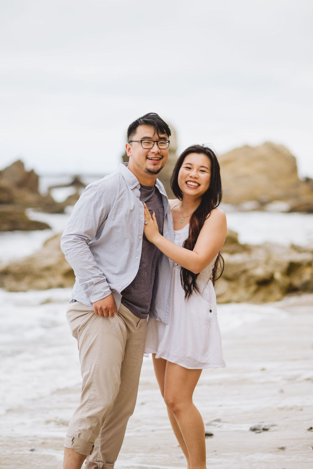 A couple poses for engagement photos at Corona del Mar, capturing the romance and natural beauty of the beach.