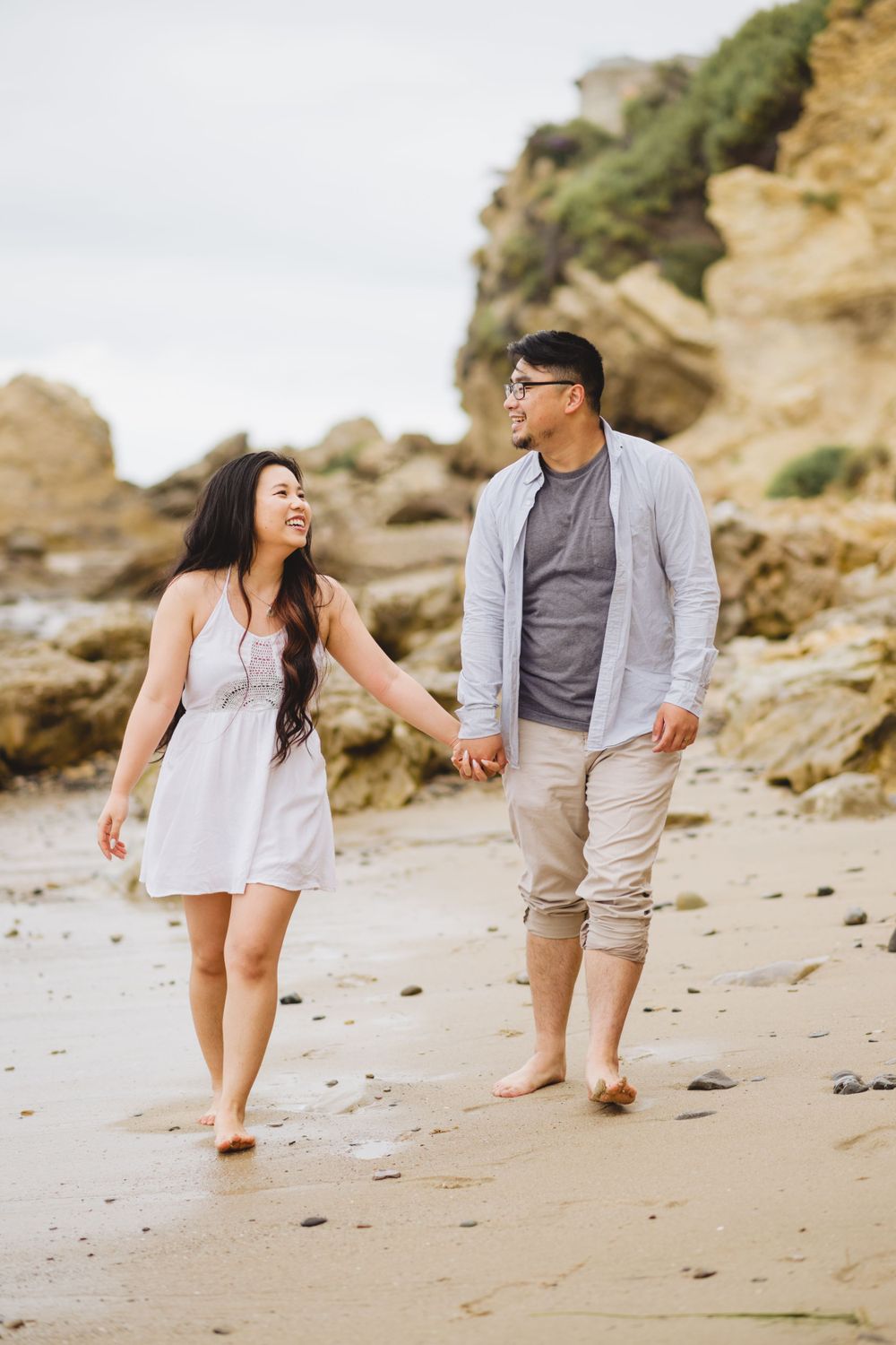 A couple poses for engagement photos at Corona del Mar, capturing the romance and natural beauty of the beach.