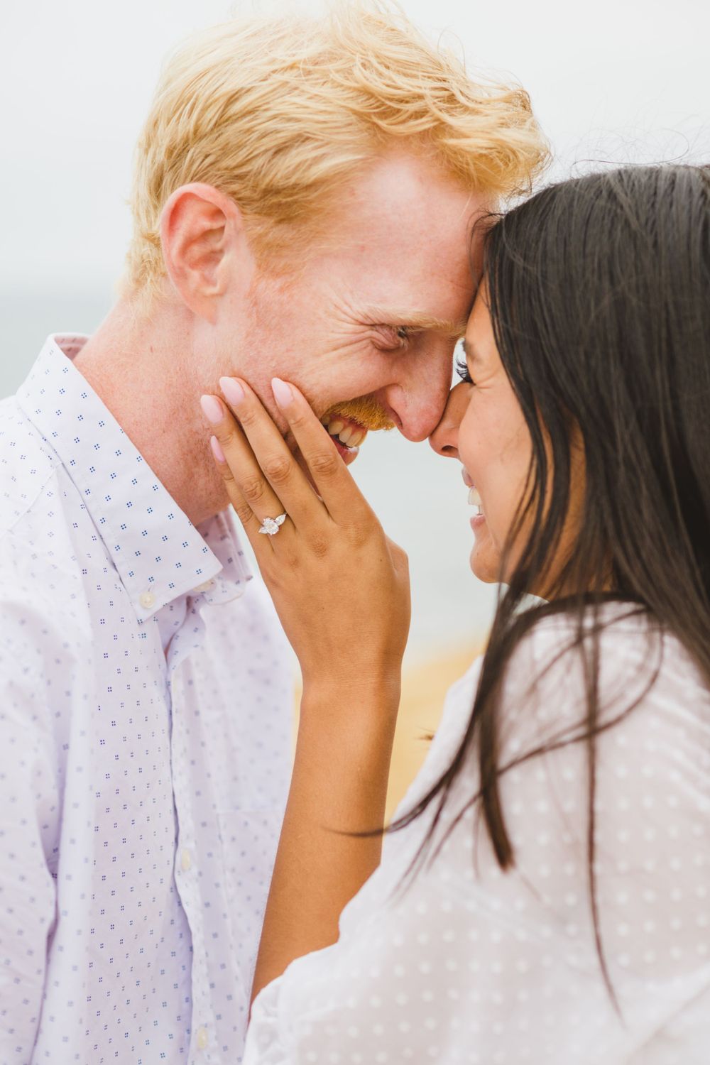 A couple shares an intimate moment together as they celebrate their engagement at a San Diego beach during sunset.