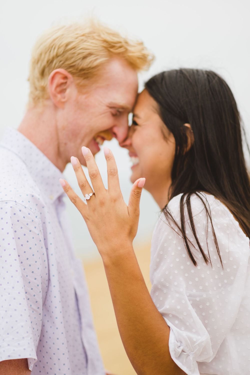 A couple shares an intimate moment together as they celebrate their engagement at a San Diego beach during sunset.