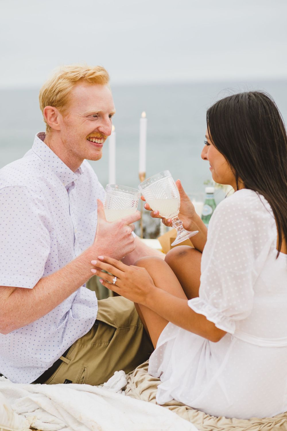 A couple shares an intimate moment together as they celebrate their engagement at a San Diego beach during sunset.