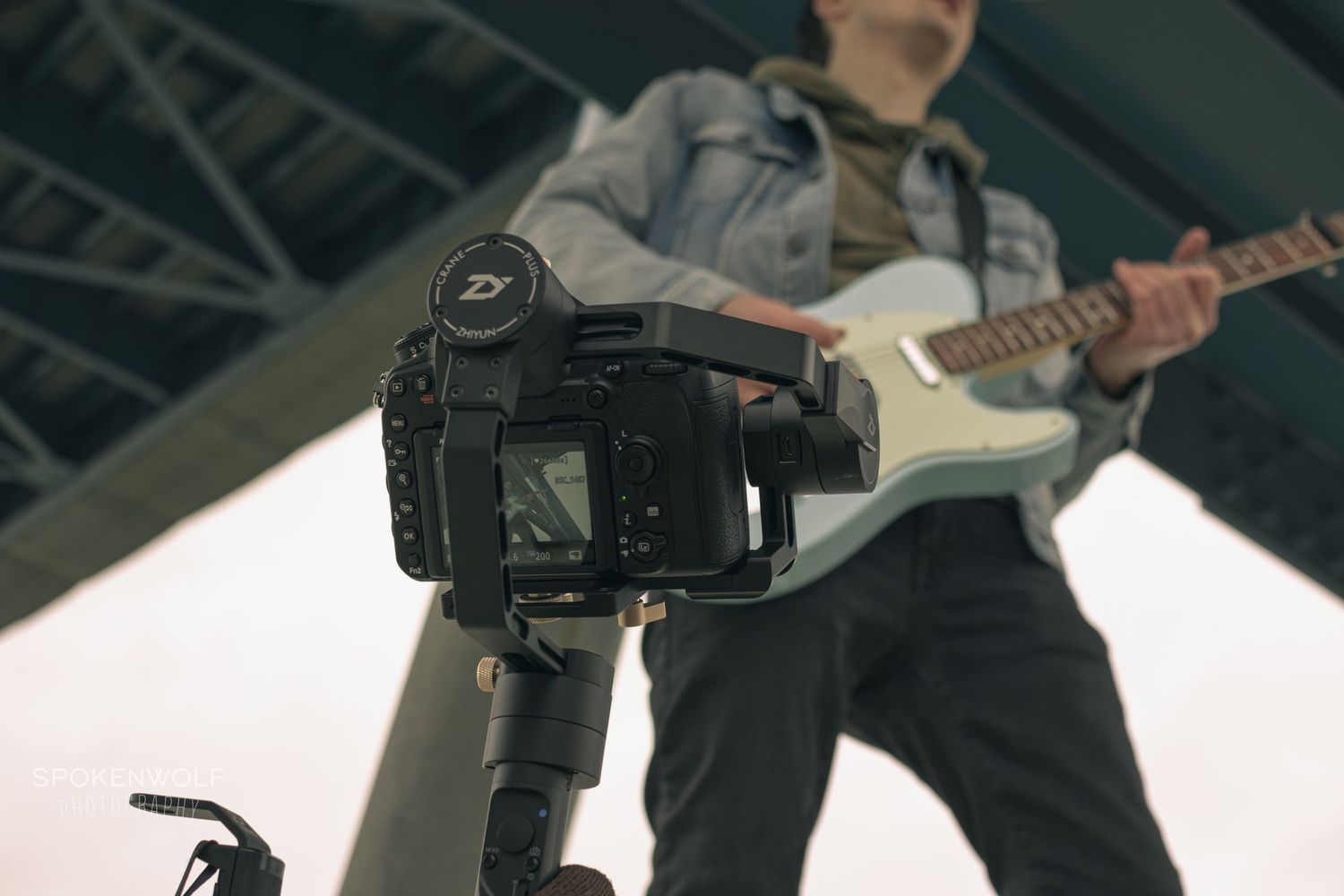 Close-up shot of a DSLR camera positioned in front of a guitarist performing on stage.