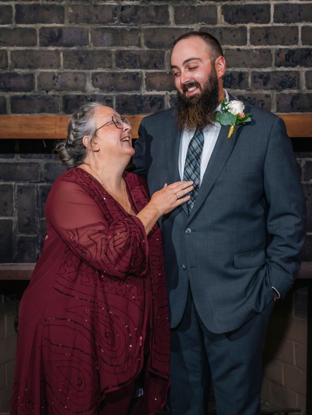 A heartwarming moment shared between two people at a formal event against a brick wall.