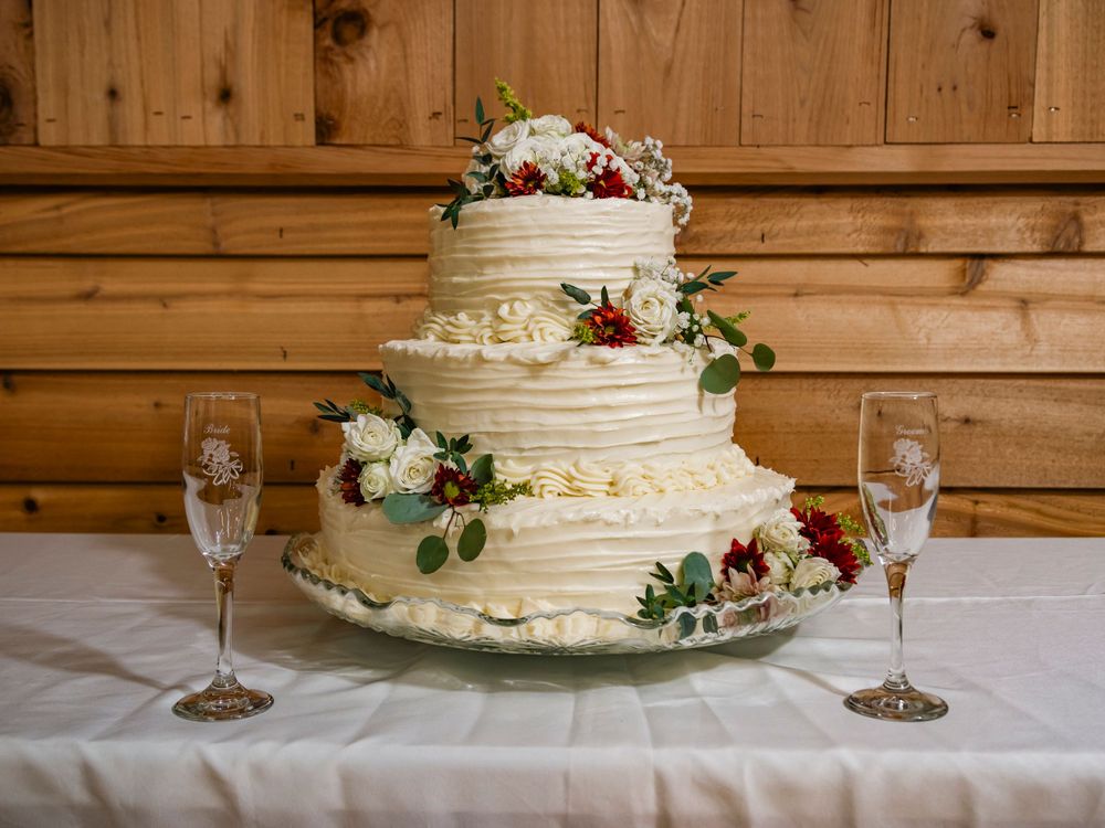 A three-tiered white wedding cake with floral decorations and champagne glasses.