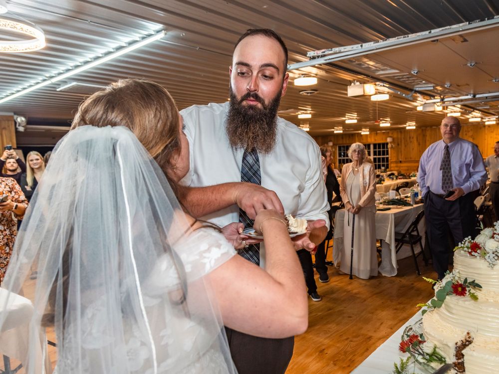 A wedding couple feeding each other pieces of cake at their reception.