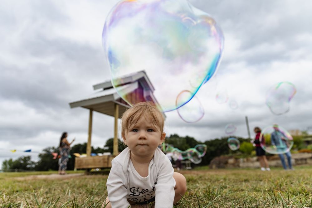 Colorful soap bubbles float through the air at an outdoor family gathering filled with joyful celebration.