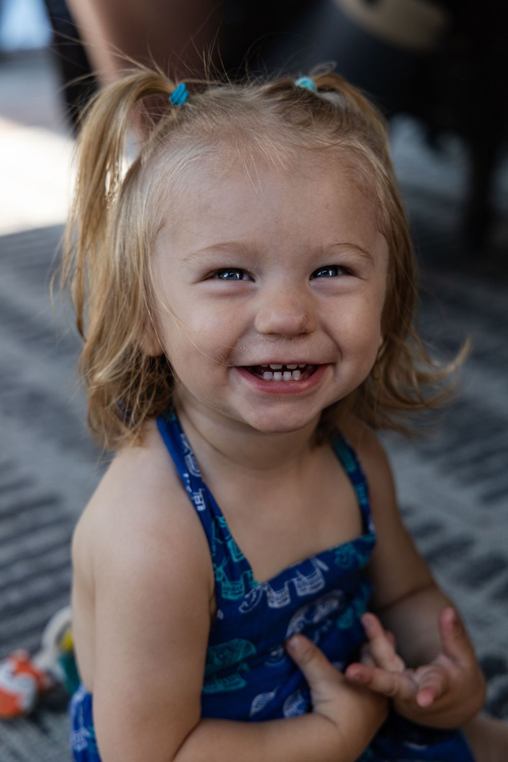 Young child wearing blue outfit smiles with joy.