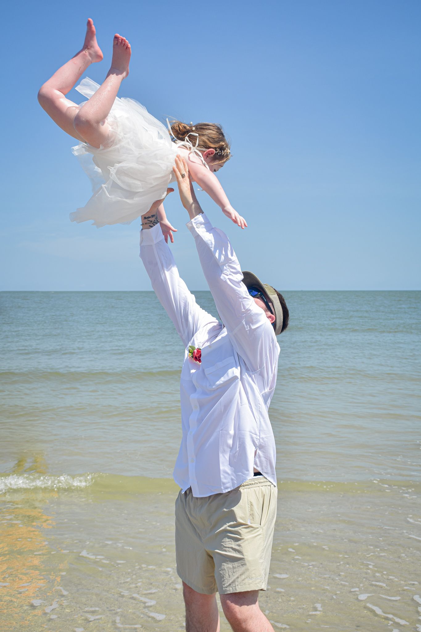 Playful moment with lifted pose on beach during wedding photoshoot.