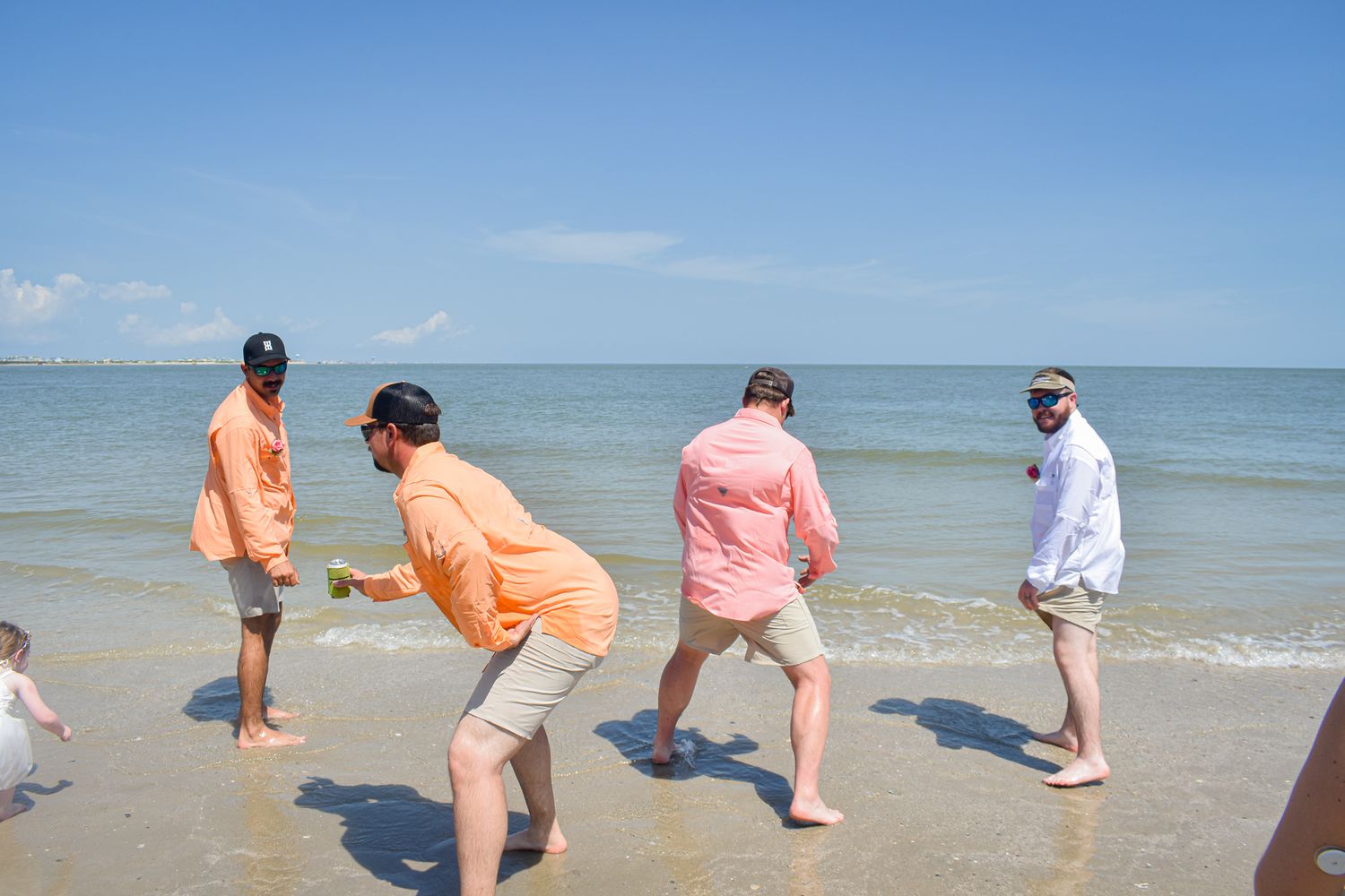 Group in coordinated orange and pink beachwear enjoying time at the ocean.