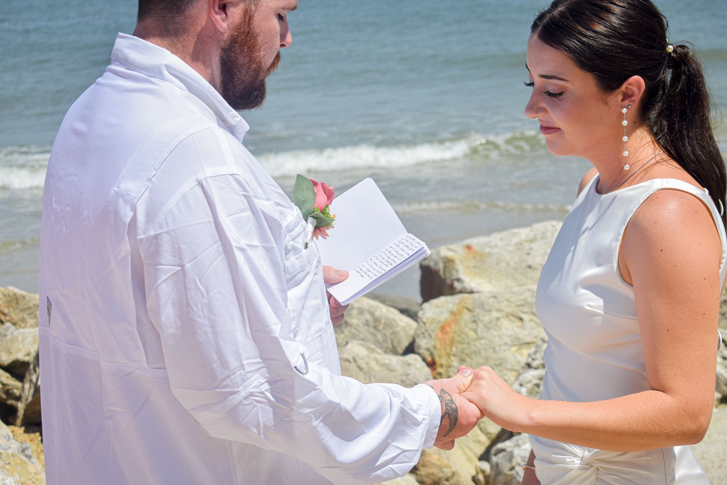 Intimate beach wedding ceremony moment between couple exchanging vows by the ocean.