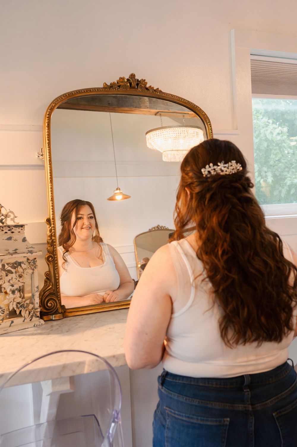 Inside a bridal salon with gold mirrors, showing backs of women in casual clothing.