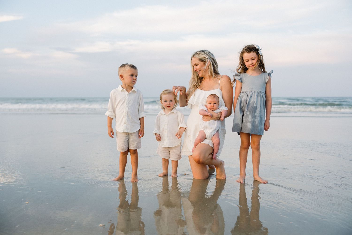 Family group enjoying time together at edge of ocean waves.
