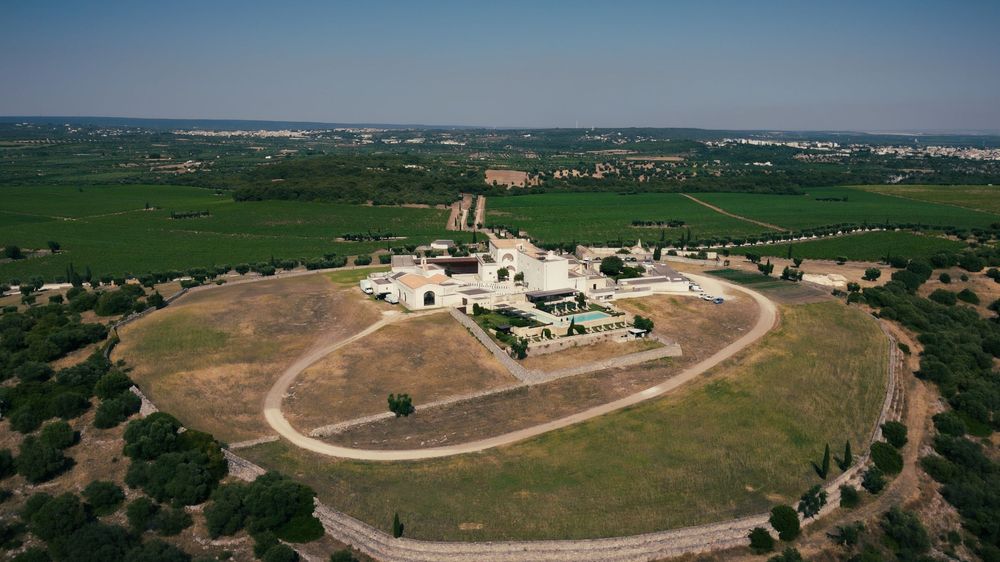 Aerial view of an isolated industrial facility surrounded by circular dirt road and green agricultural fields.