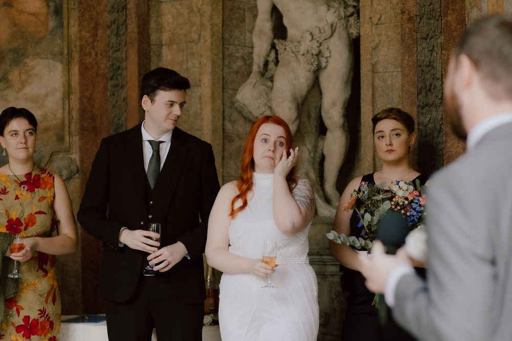 Wedding celebration scene captured in elegant stone interior with guests applauding during reception festivities.