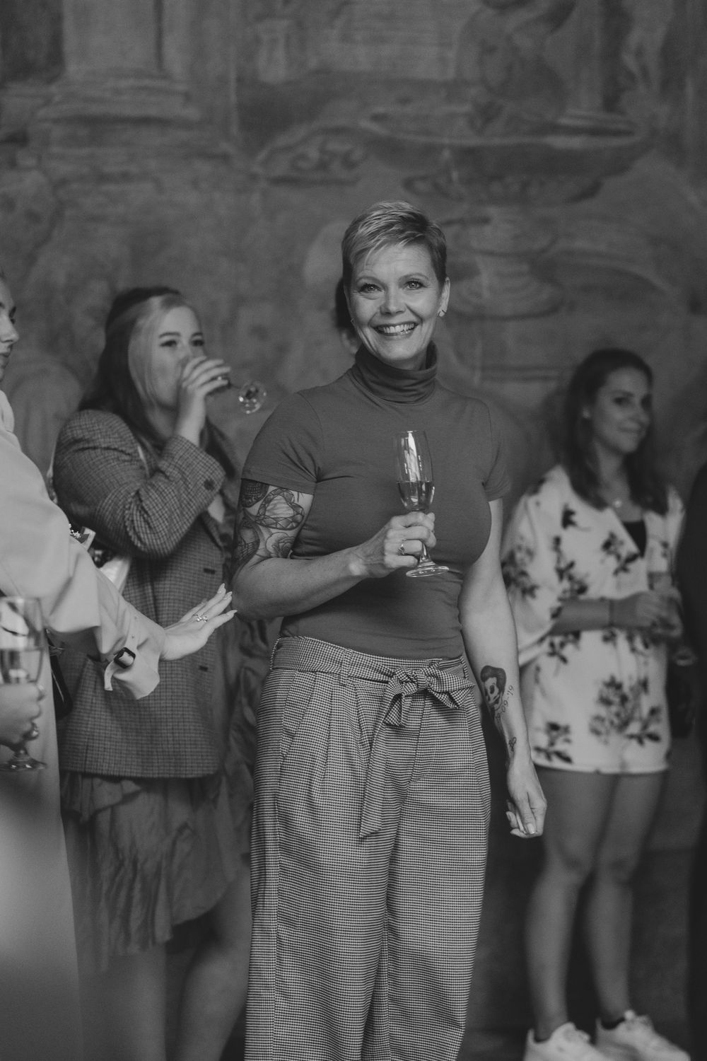 People gathered at a social event with drinks in their hands, sharing smiles and laughter in a candid moment.