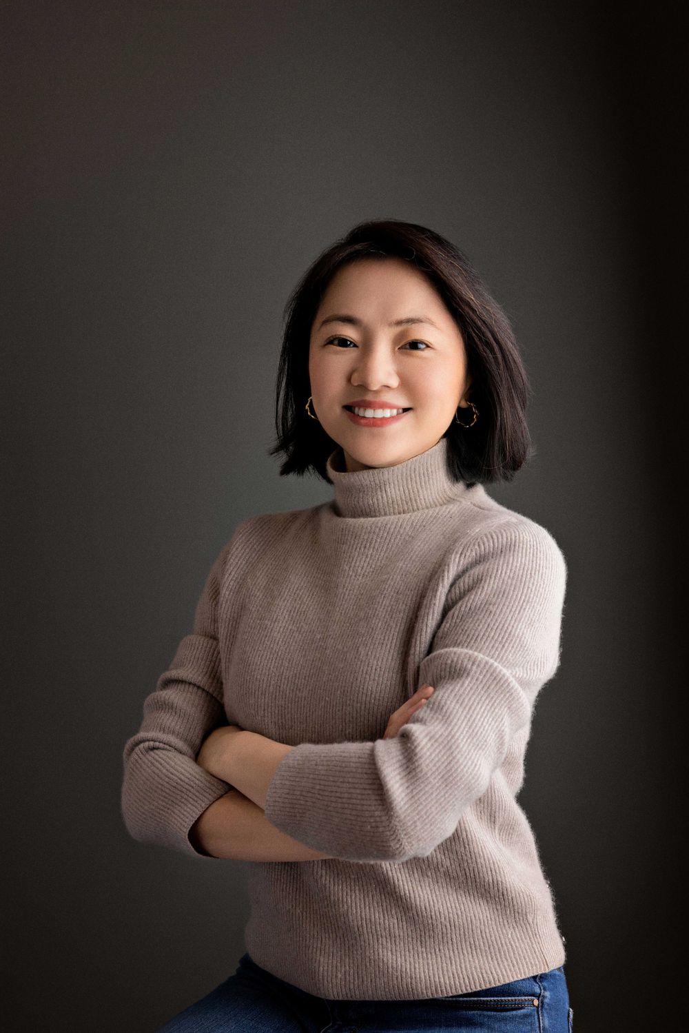 Casual portrait in beige sweater with crossed arms and natural smile.