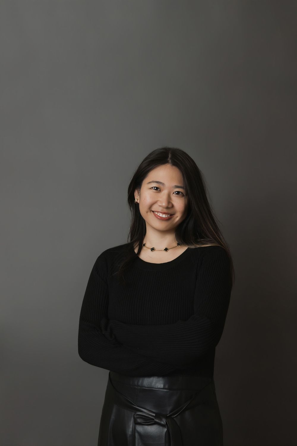 A person in a black sweater poses against a gray background with varying expressions in a photo series.