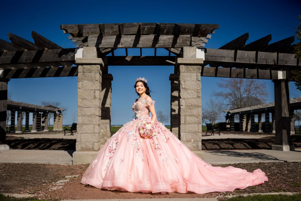 Quinceañera posing in a pink ballgown under a wooden garden structure. Elegant XV portraits in Lake County by Alex T Photography.