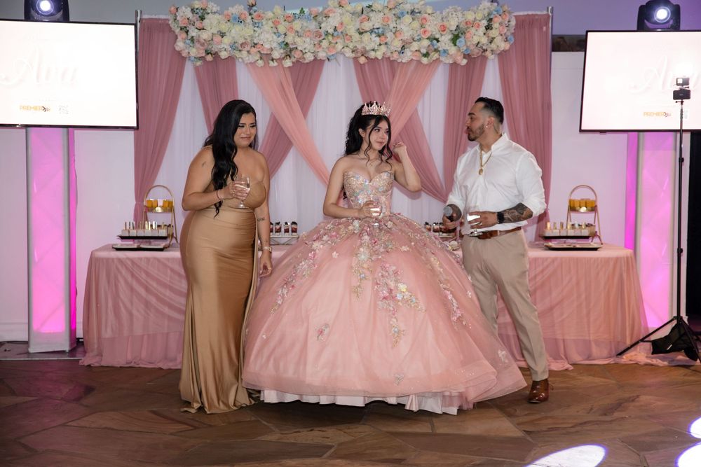 Anayya posing with her parents at the head table. Elegant Quinceañera reception details at Salon Latino captured by Alex T Photography.