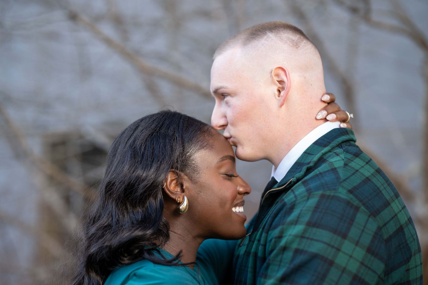Romantic engagement photos of couple embracing outdoors in casual attire.
