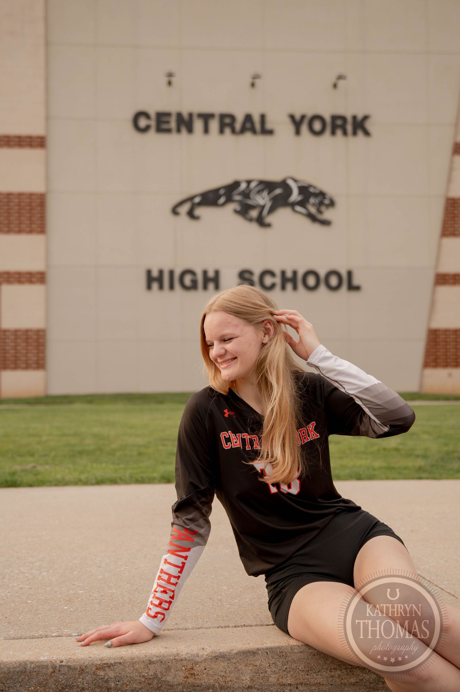 A student poses outside Central York High School wearing a black athletic shirt and shorts on a sunny day.