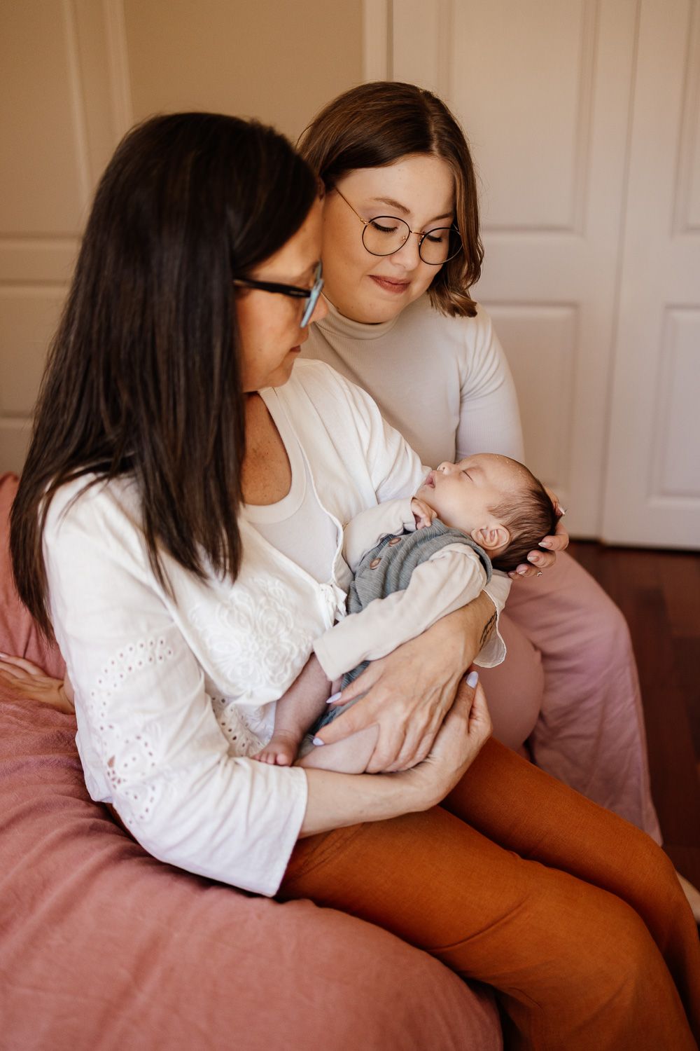 A mom and grandma hold their new baby together