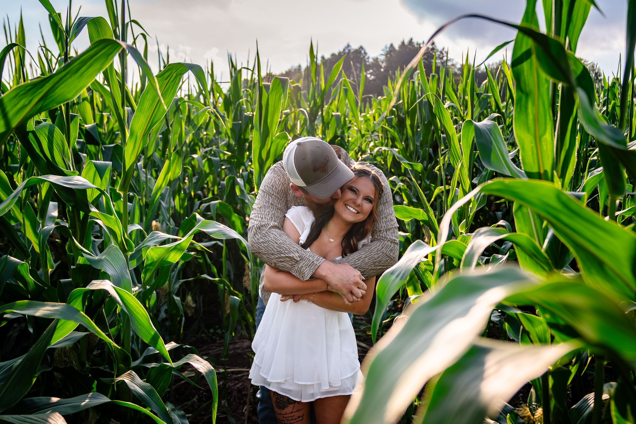 Couple embracing in a lush green cornfield on a sunny summer day.