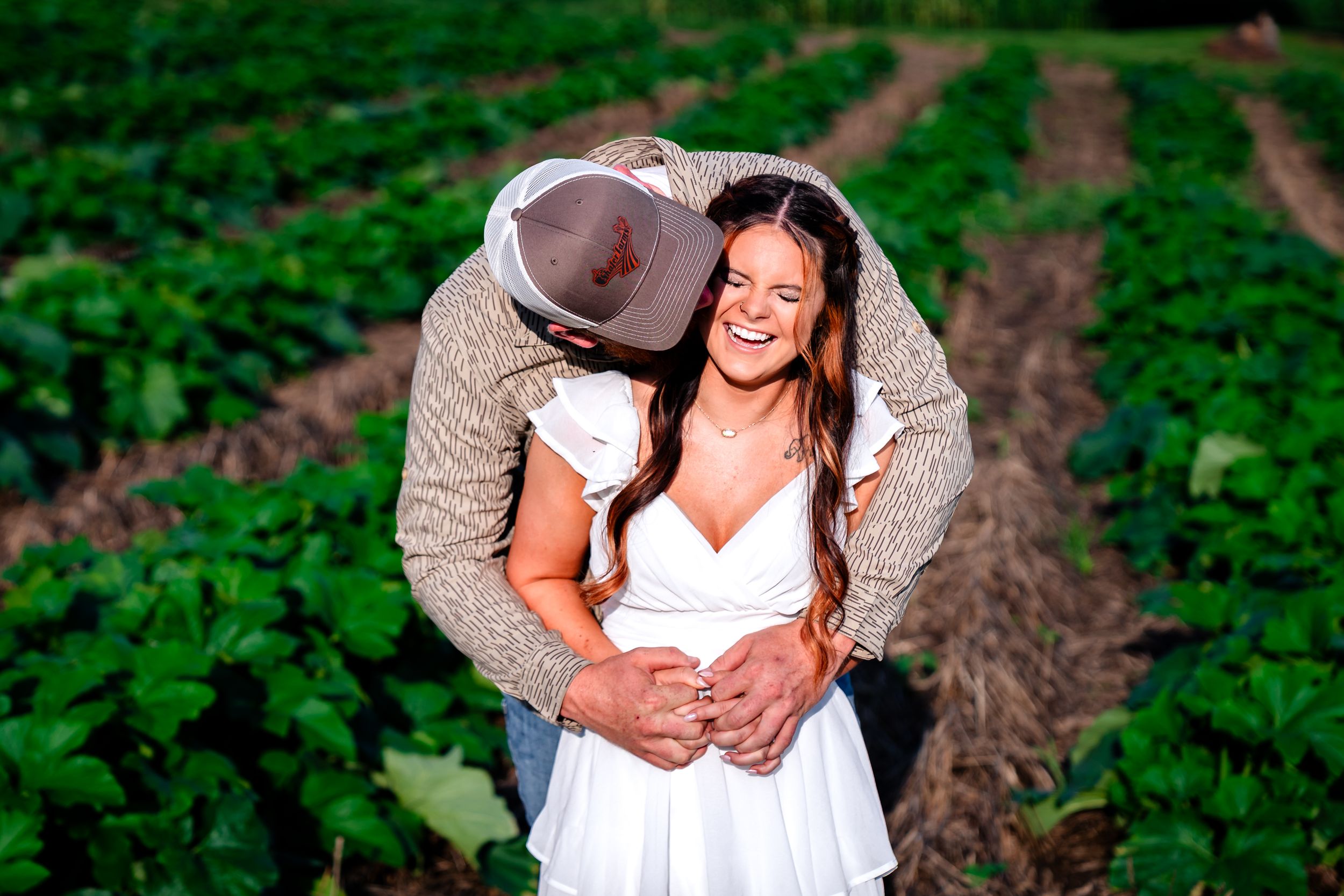 Intimate moment captured between couple in a verdant agricultural field.