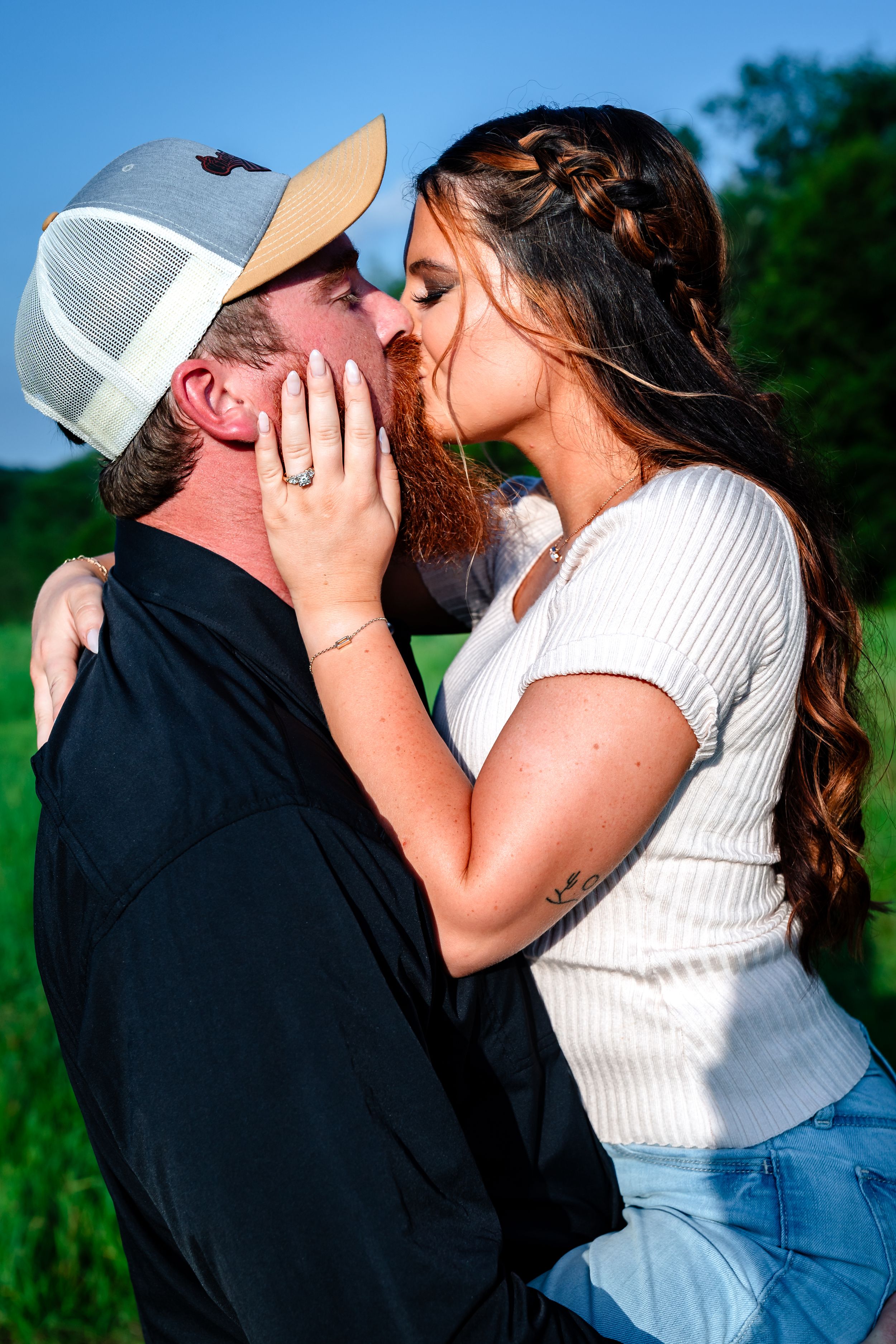Tender moment shared between couple in casual summer attire against natural backdrop.