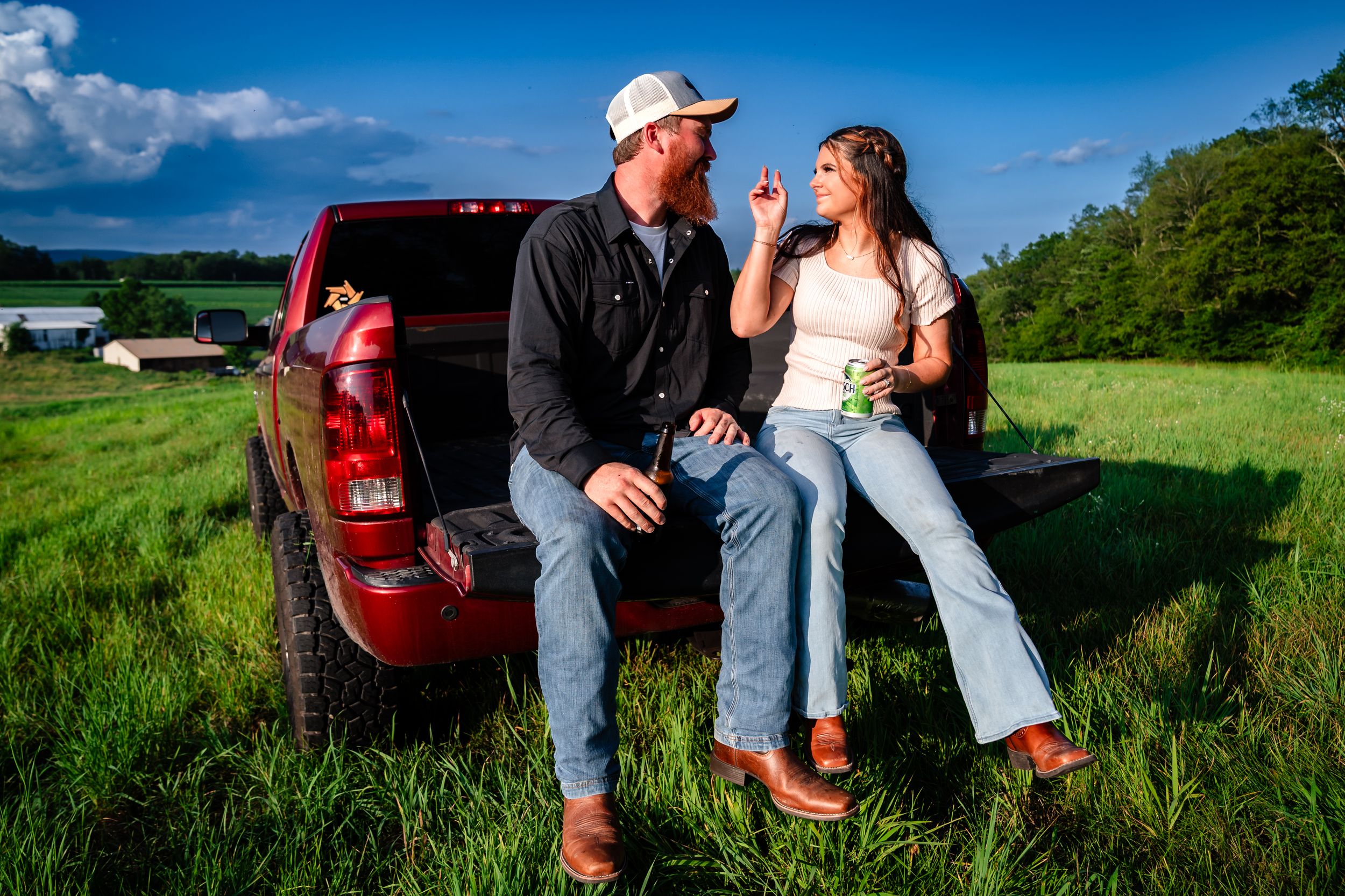 Casual countryside photoshoot with red truck in background on sunny day.