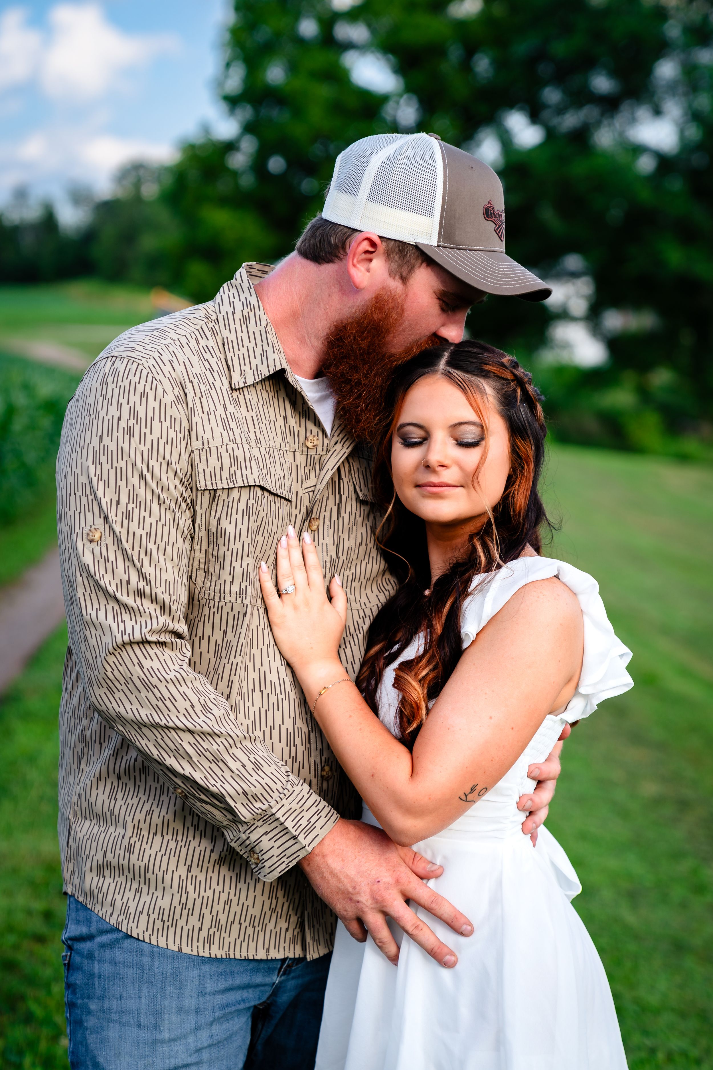 A tender embrace between a couple on a rural path with cornfields in the background.