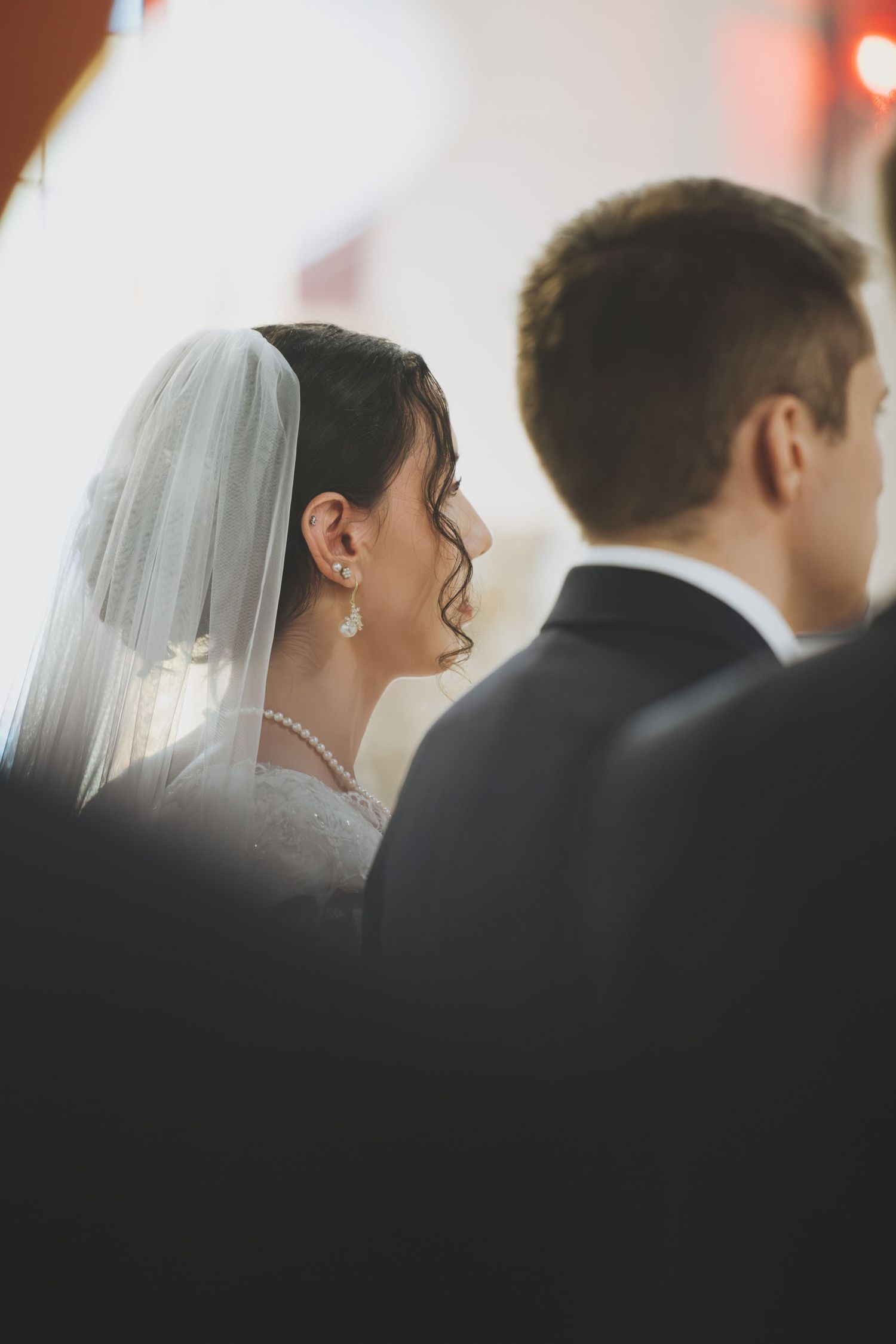 A soft-focus wedding photo sequence showing a bride in a veil against warm lighting with a silhouetted figure beside her.