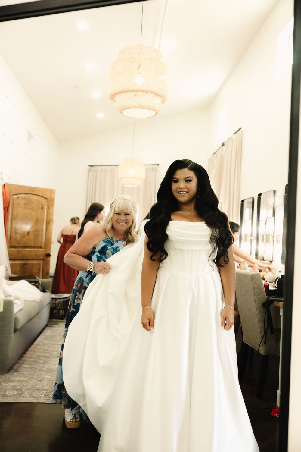 A stunning white wedding dress being fitted in a bridal boutique with elegant lighting and decor.