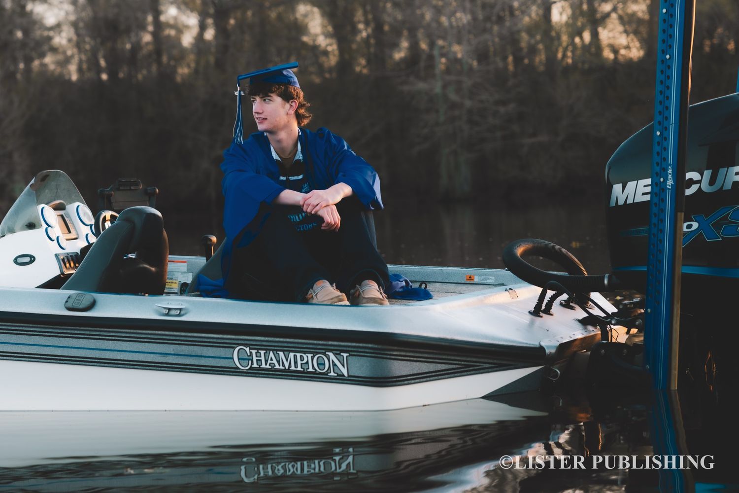 Person in blue cap sitting on white Champion fishing boat at sunset.